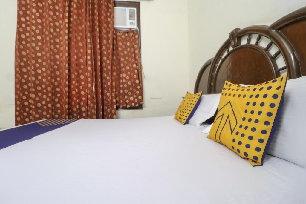 a bedroom with a bed with yellow and blue pillows at SPOT ON Motel Haryana in Chandīgarh