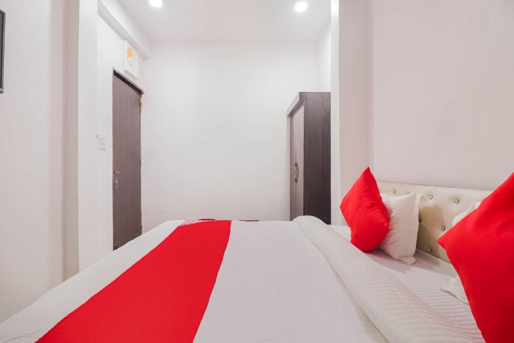 een wit bed met rode kussens in een kamer bij SPOT ON Royal Inn in Charbagh