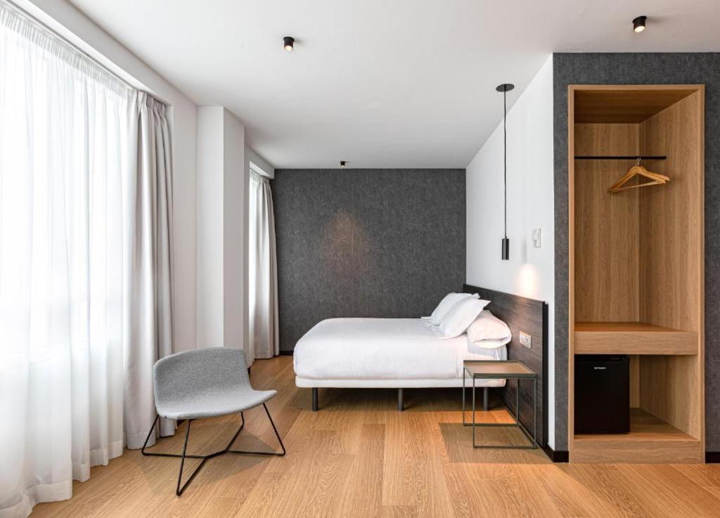 een slaapkamer met een bed, een bureau en een stoel bij Hotel Forum Ceao in Lugo