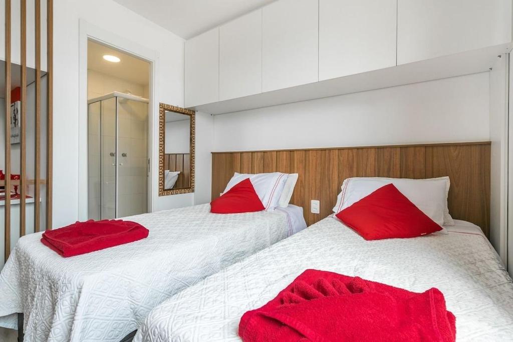 1 dormitorio con 2 camas y almohadas rojas en Impactante Studio no Brás com Piscina/Metrô Brás, en São Paulo