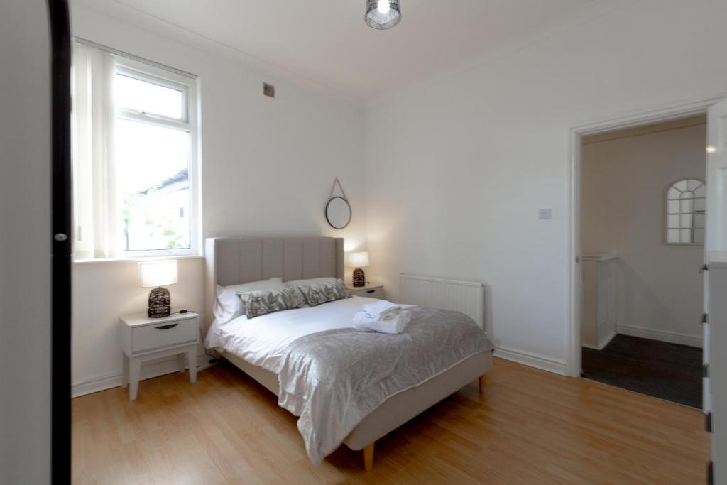 a white bedroom with a bed and two windows at Liverpool Haven: Charming Private Room in Liverpool