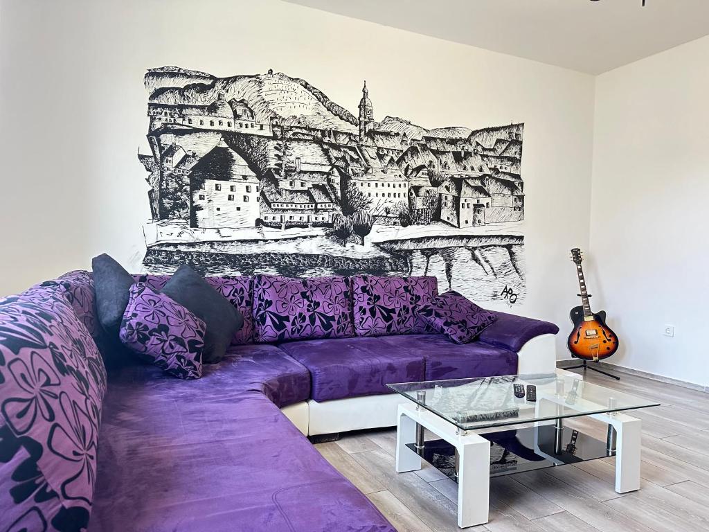 un sofá púrpura en una sala de estar con un mural en Maribor Central Apartment (Garden + Free Parking) en Maribor