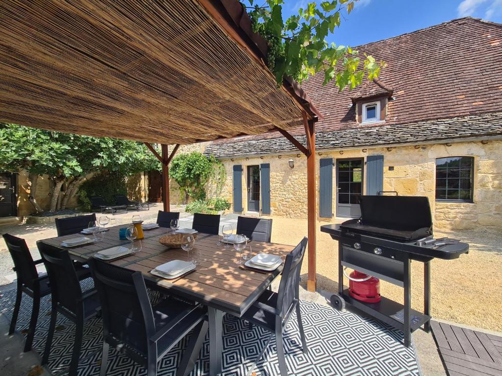 een tafel met stoelen en een piano op een patio bij La Noz Vad, Superbe maison Perigourdine in Saint-Cybranet