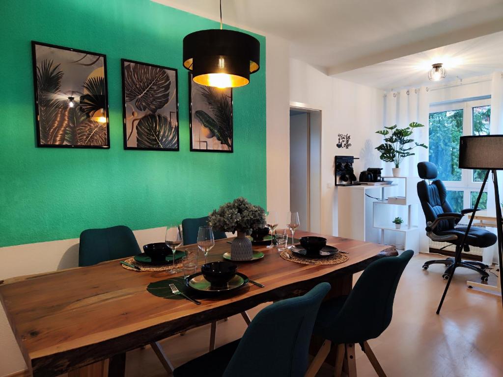 een eettafel met stoelen en een groene muur bij 2 Zimmer Wohnung, Küche, Bad, Balkon, Tiefgarage, Netflix in Alzey
