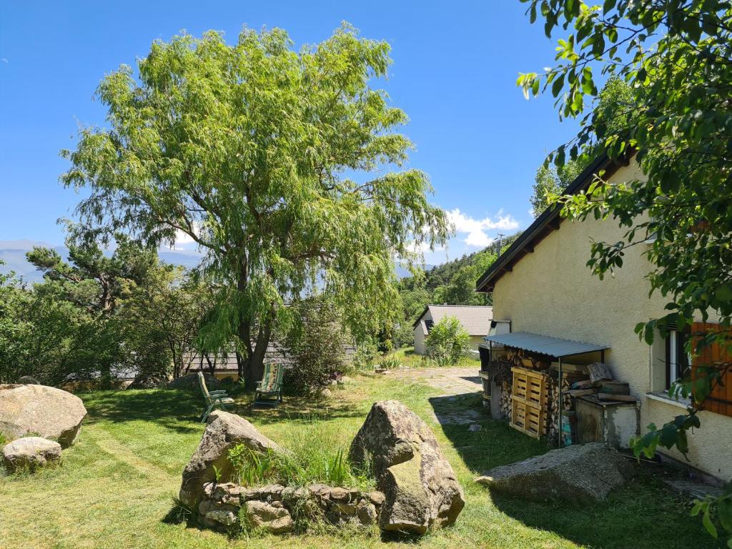 a house with rocks and a tree in the yard at Chalet Le Parc de Latour, au pied de la montagne in Latour-de-Carol