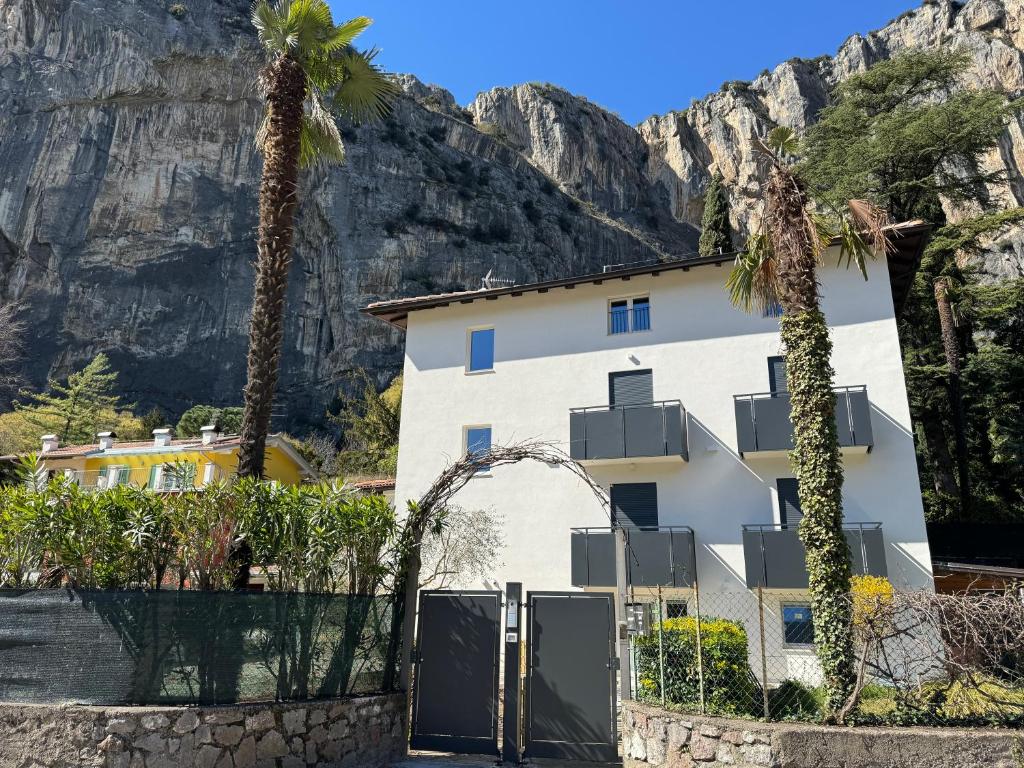 a white building with palm trees and mountains in the background at Casa Prabi in Arco