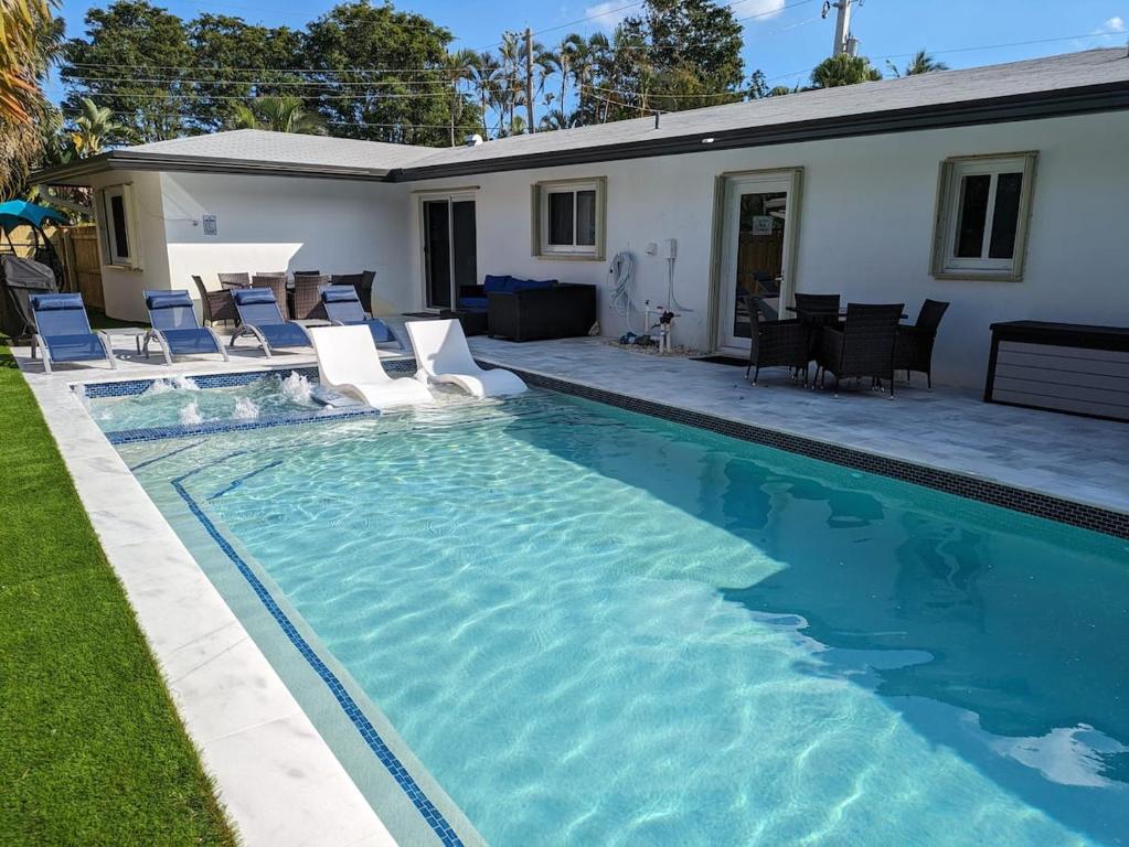 een zwembad met stoelen en een huis bij Cozy Fun-Size Getaway + Pool&Spa 5 mins to Beach in Fort Lauderdale