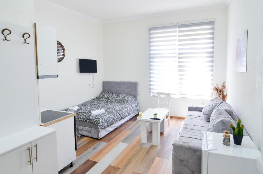 a white living room with a couch and a bed at Central Vista Apartments Sarajevo in Sarajevo