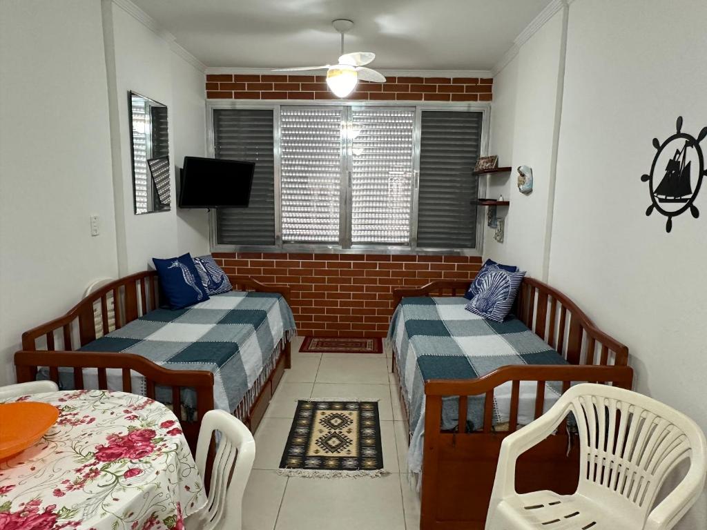 a small room with two beds and a table at Apartamento Pé na Areia - Praia Grande in Praia Grande