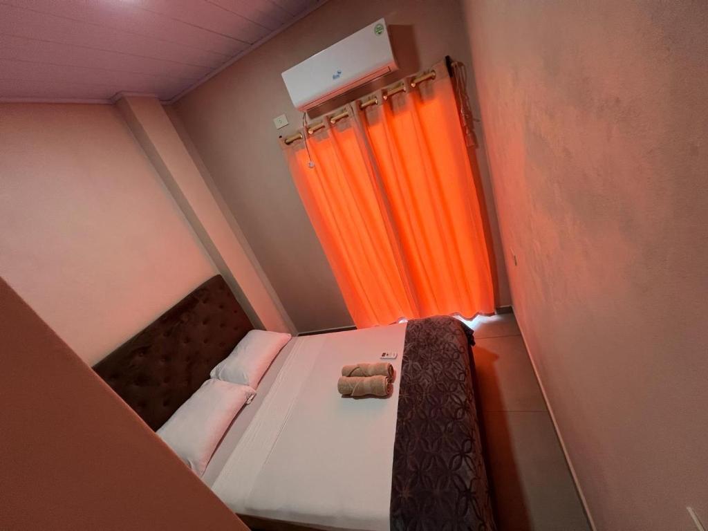 ein kleines Bett in einem kleinen Zimmer mit orangefarbenem Vorhang in der Unterkunft Hospedaje Lucas in El Soberbio