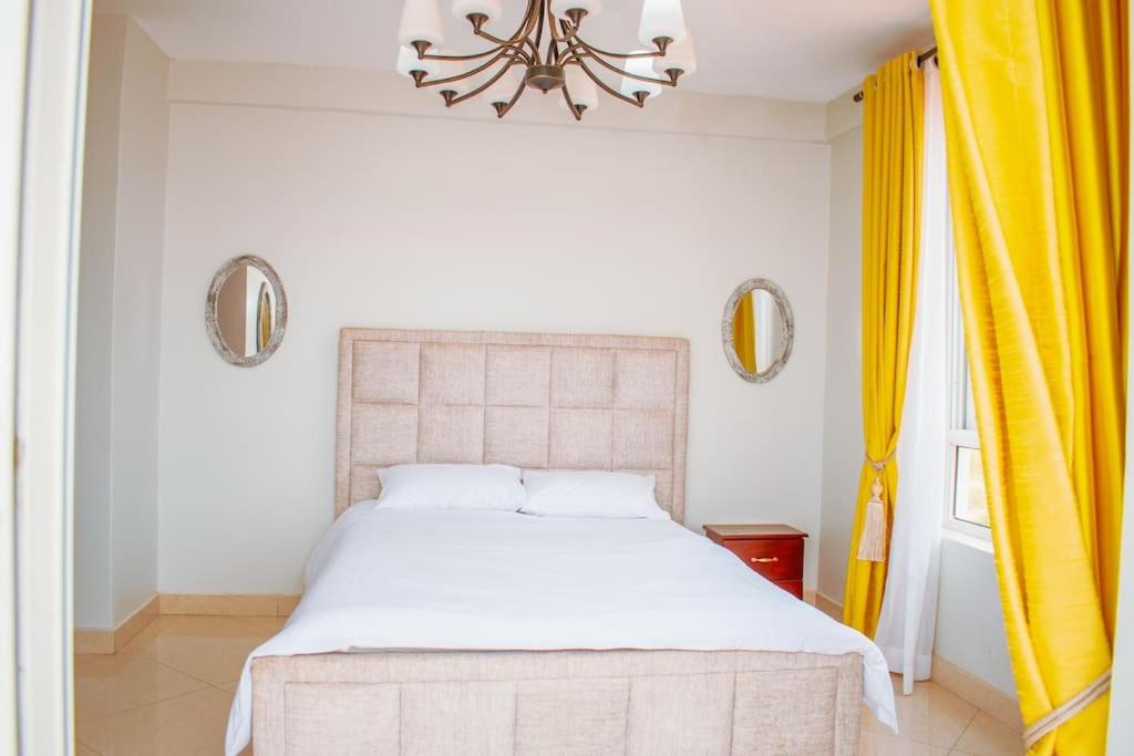 a bedroom with a large white bed and a chandelier at Summer in Garuga in Entebbe
