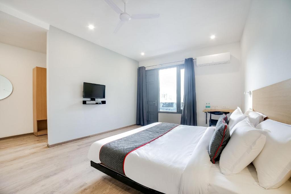 una camera con un grande letto bianco e una TV di Super Townhouse 213 Artemis Hospital Near Appu Ghar a Gurgaon