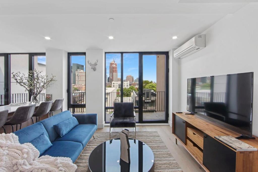 uma sala de estar com um sofá azul e uma televisão em 149BK-601 NEW PH 2BR-2Bath Private Rooftop W D em Brooklyn