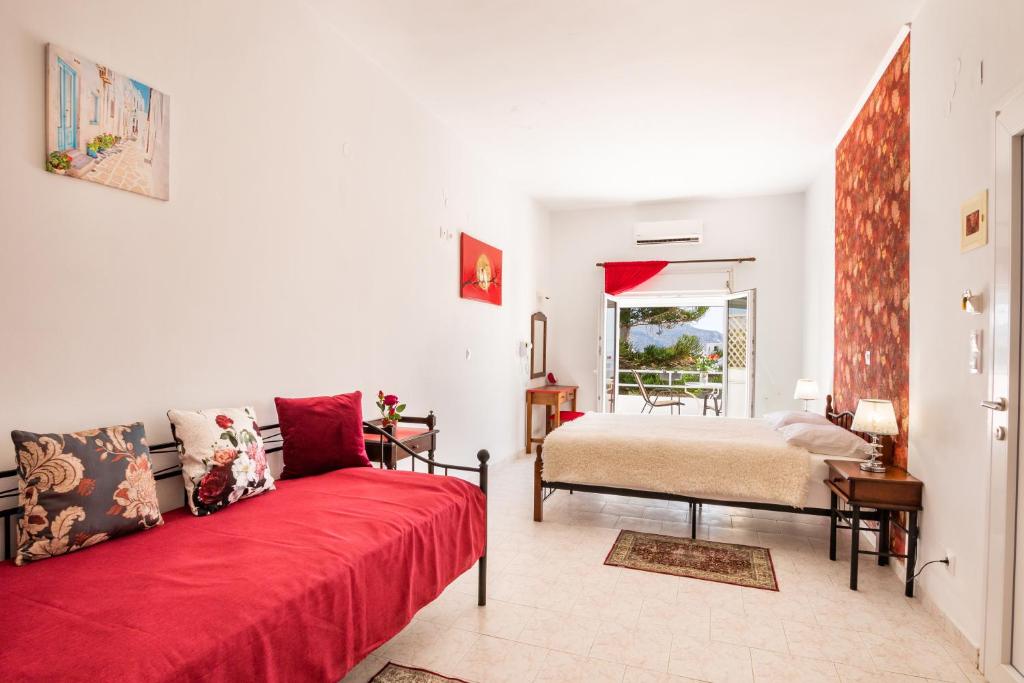 a living room with a red couch and a bed at Perama Hotel, Karpathos in Amoopi