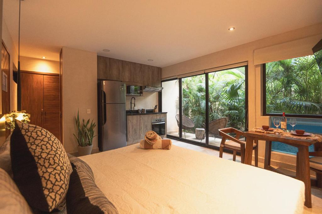 ein Schlafzimmer mit einem Bett und eine Küche mit einem Tisch in der Unterkunft Cacao Tulum - Studio with Exterior Plunge Pool Washer & Dryer in Tulum