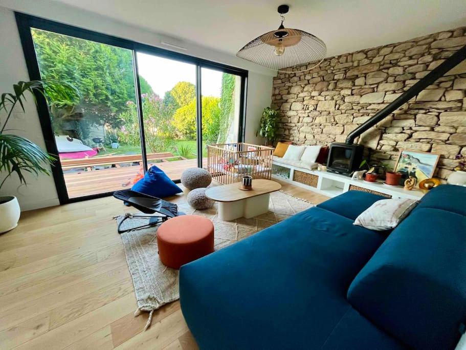 - un salon avec un canapé bleu et un mur en pierre dans l'établissement Maison familiale au calme, à Lorient