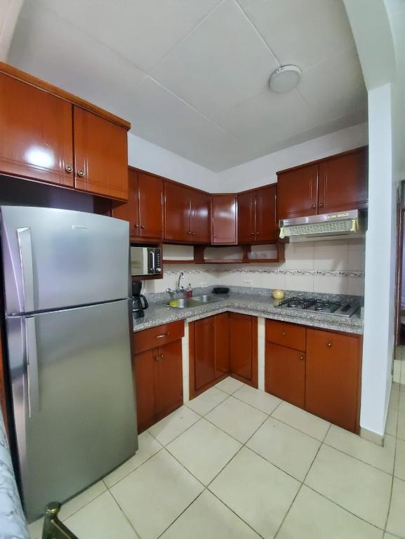 a kitchen with wooden cabinets and a stainless steel refrigerator at SUITE AMOBLADA CERCA DEL MALL DEL RIO in Cuenca