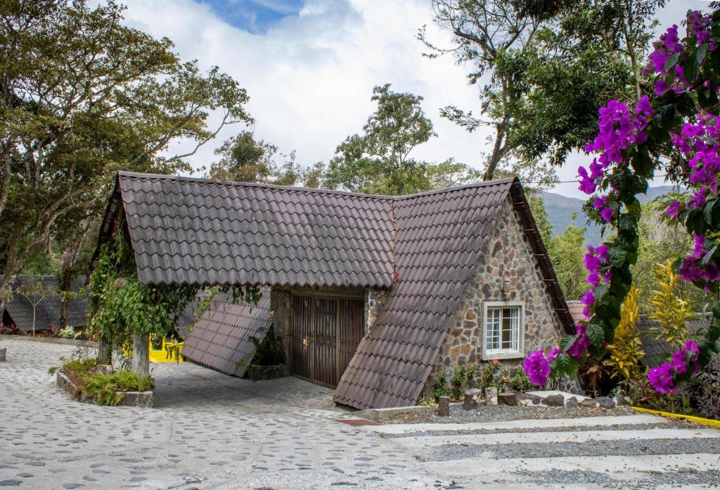 une maison avec un toit rayé et des fleurs dans l'établissement Refugio Cariguana, à El Valle de Antón