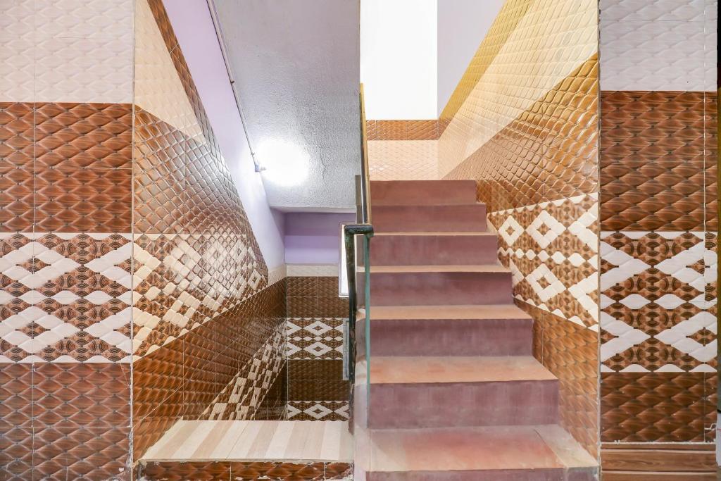 una escalera de caracol con baldosas de cobre en la pared en OYO Mk Lodge, en Madurai