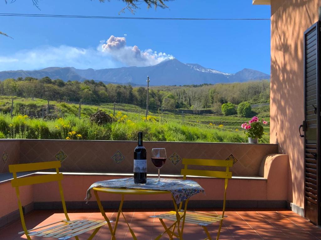 a table with a glass of wine on a balcony with a view at Tenuta Kiwi dell’Etna in Milo