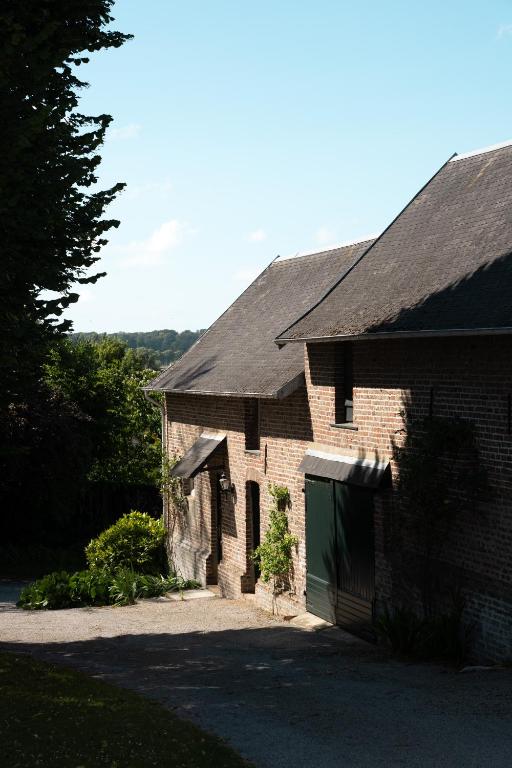 une maison en briques avec un garage et une allée dans l'établissement Maison Maa , corps de ferme en entier, à 5 min de Saint Valery sur Somme à pieds le long du canal, à Boismont