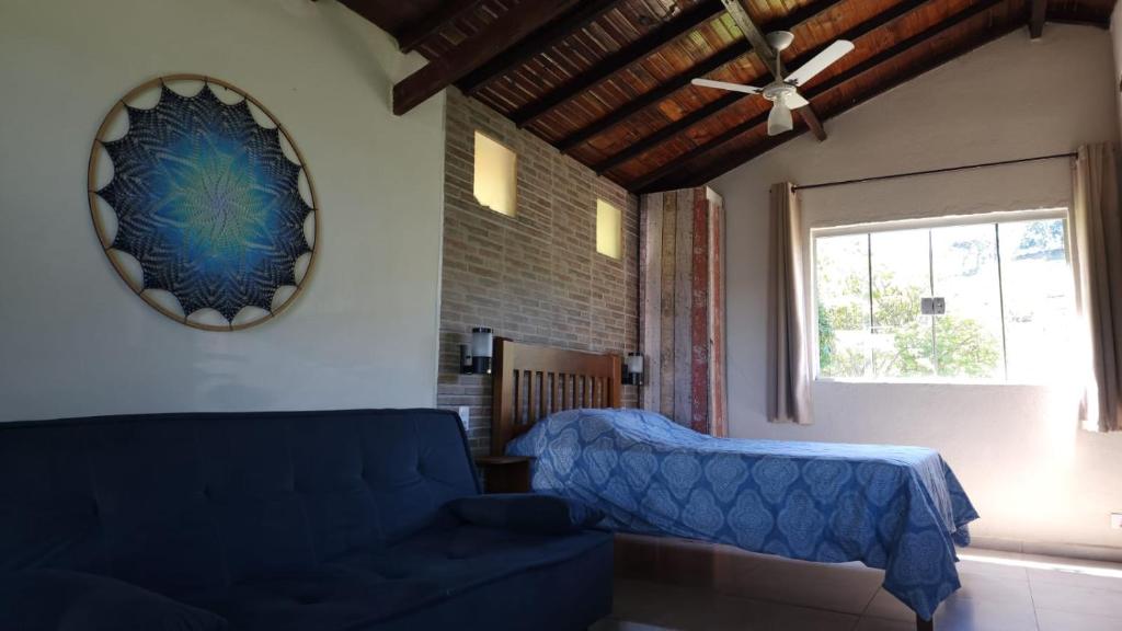 een woonkamer met een blauwe bank en een raam bij Chalés Recanto das Flores in Bueno Brandão