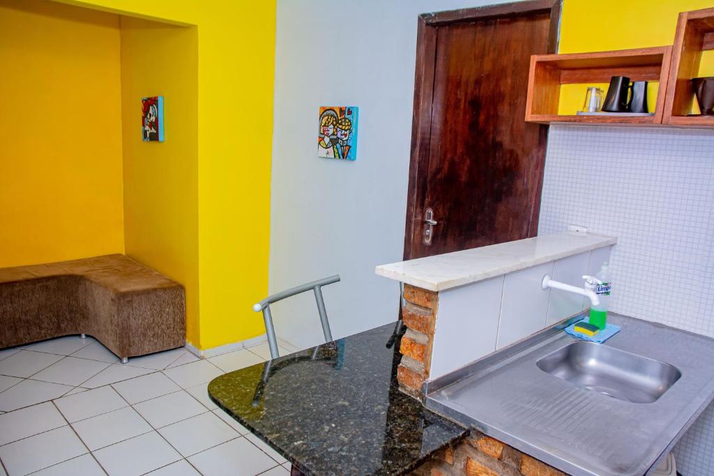 a kitchen with a sink and a table with a chair at Pousada Flat Castor in Natal