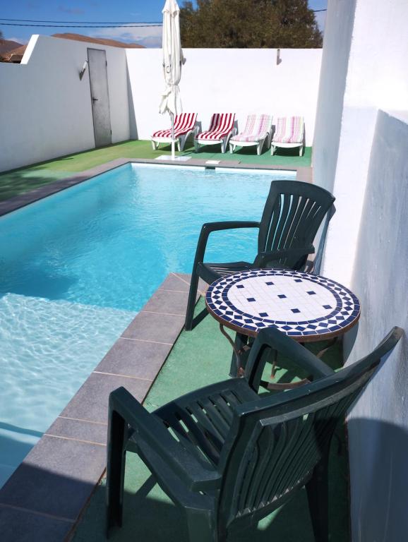 - deux chaises et une table à côté de la piscine dans l'établissement LA CALDERETA CASA RURAL, à La Oliva