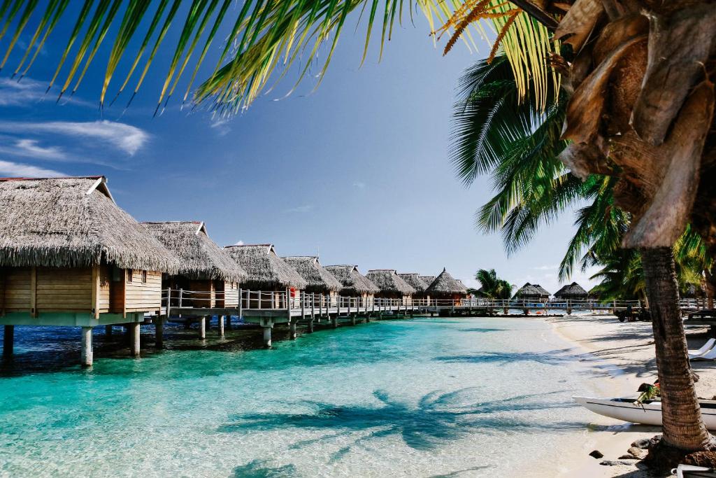 einen Strand mit einer Reihe von Hütten auf dem Wasser in der Unterkunft Manava Beach Resort & Spa Moorea in Maharepa