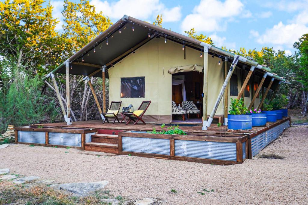une maison avec une terrasse couverte et une terrasse dans l'établissement Hill Country Safari Tent and Recreational Pavilion and Cowboy Pool!, à Dripping Springs