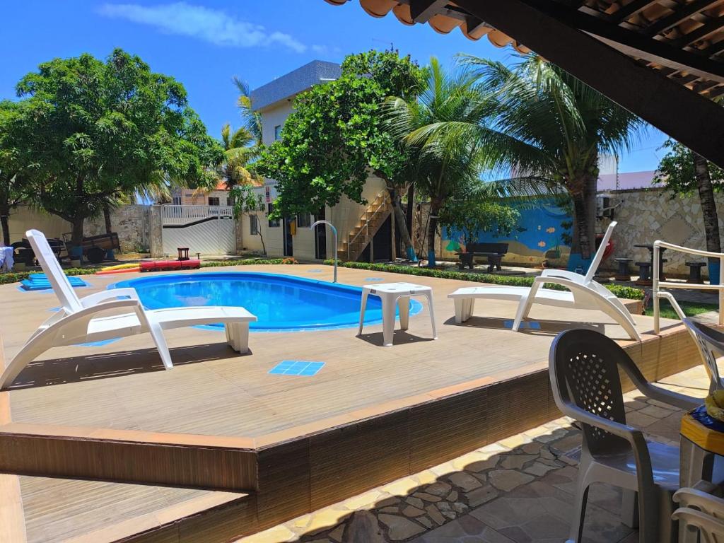 a wooden deck with chairs and a swimming pool at Pousada Bem-te-vi in Aracaju