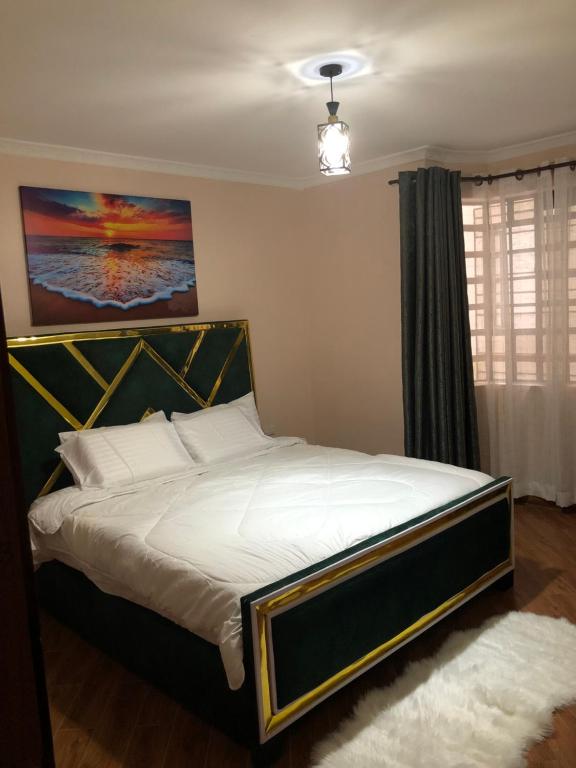 a bedroom with a large bed with white sheets at Vogue Homes in Nakuru