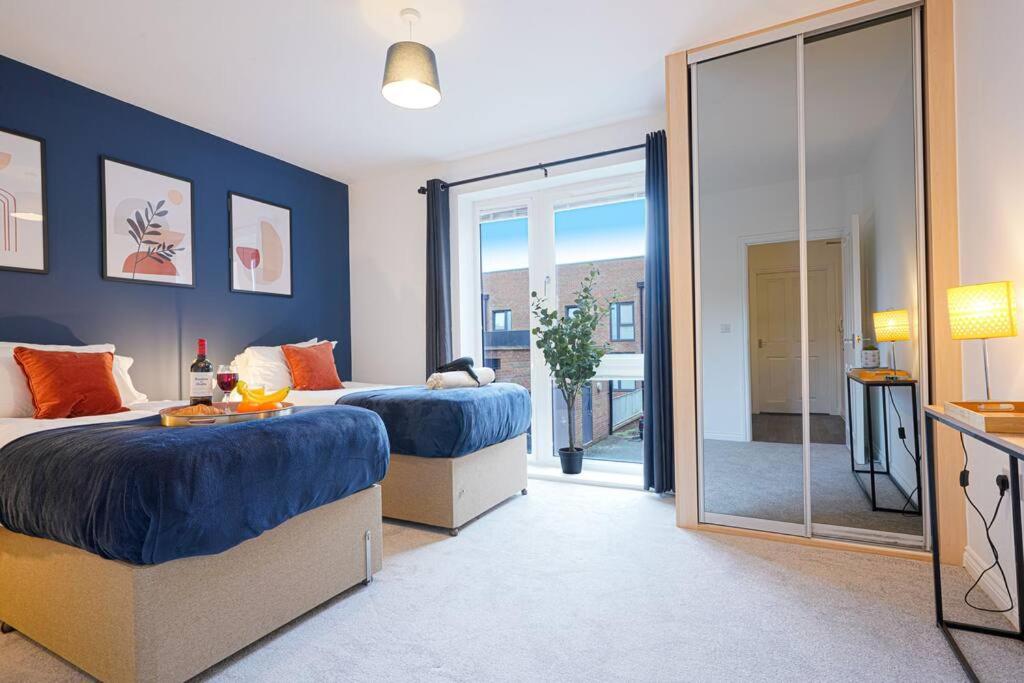 een slaapkamer met 2 bedden en een glazen schuifdeur bij Luxury Campbell Park Apartments in Central MK with Balcony, Free Parking & Smart TV with Netflix by Yoko Property in Milton Keynes