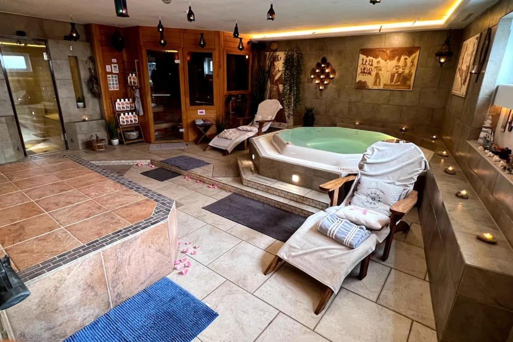 een badkamer met een bad en stoelen en een bad bij Marcel Bruckmanns Spa - Wellness & Holiday Apt. in Erkrath