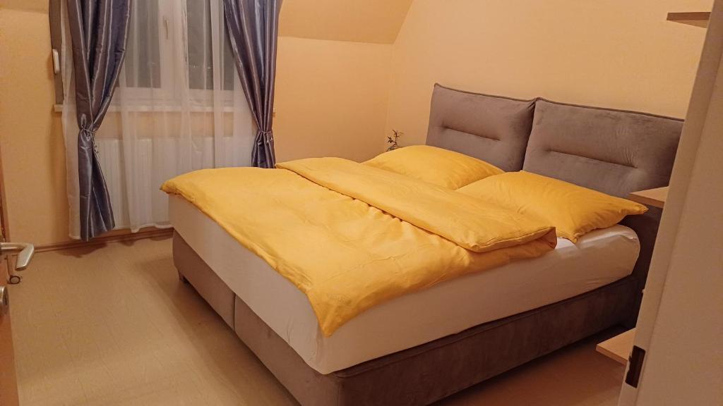 a bedroom with a bed with yellow sheets and a window at Alex & Nicol in Gänserndorf