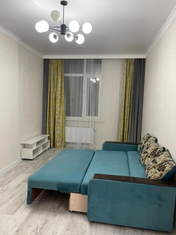 a living room with a blue couch in a room at Уютная квартира рядом с вокзалом Нурлы-Жол in Promyshlennyy