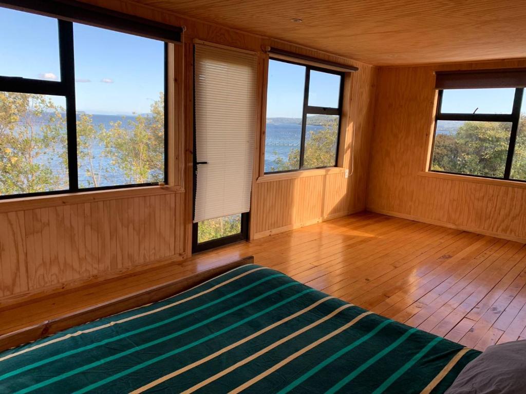 a bedroom with windows and a bed in a room at ARRIENDO DIARIO PUQUELDON-CHILOE, SECTOR PLAYA LINCAY in Puqueldón
