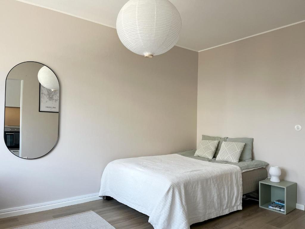 1 dormitorio con cama y espejo en Garden city studio, en Espoo