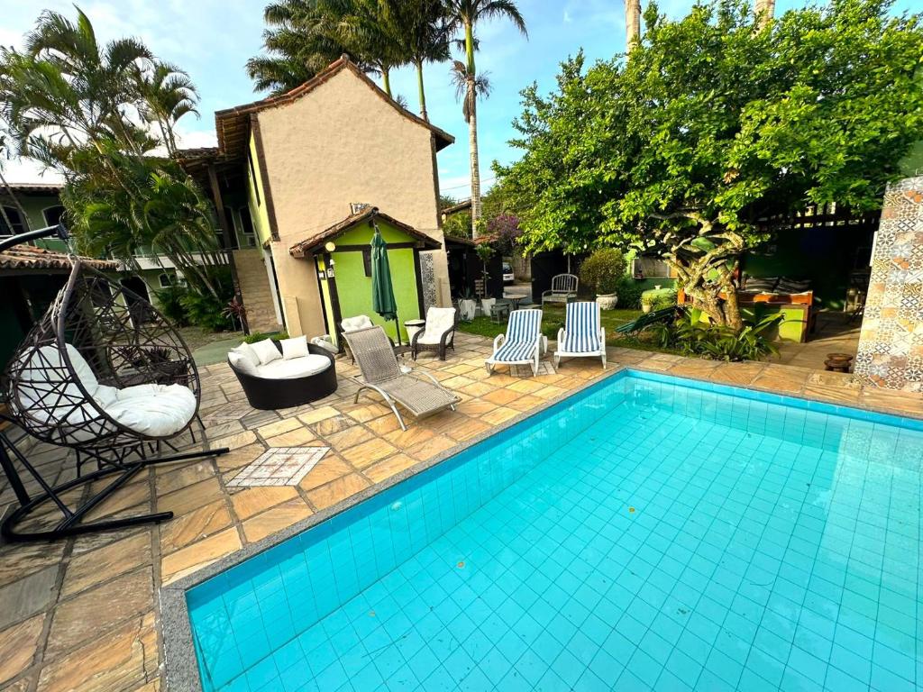 a swimming pool with chairs and a house at Repouso das Flores in Búzios