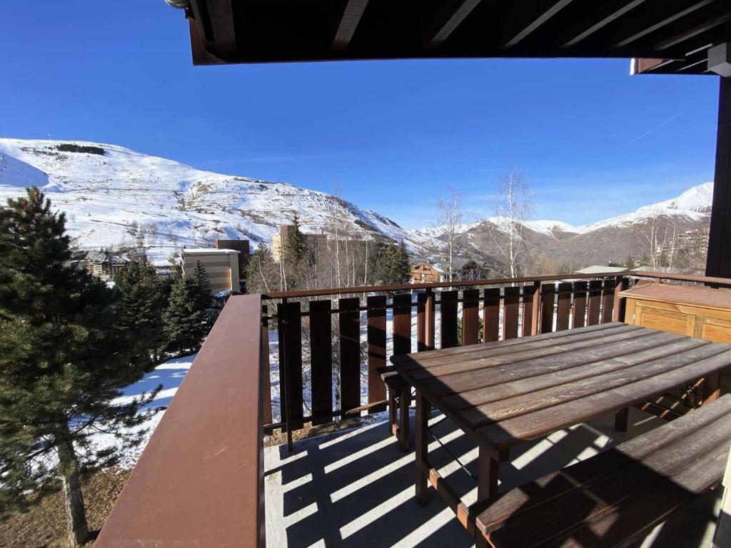 a wooden bench on a balcony with snow covered mountains at Résidence Meije - Pièces 341 in Vénosc