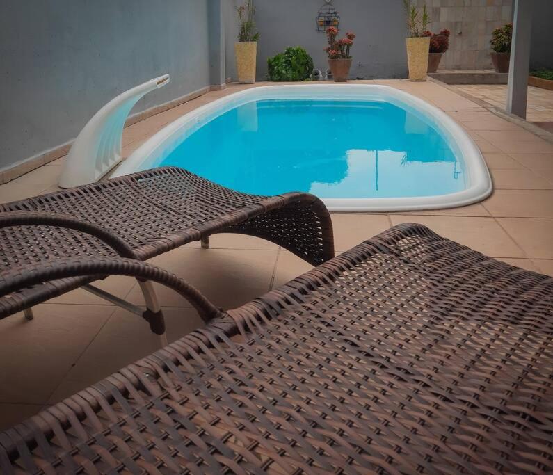 un banco de mimbre sentado junto a una piscina en Residencial Celedone en Boa Vista