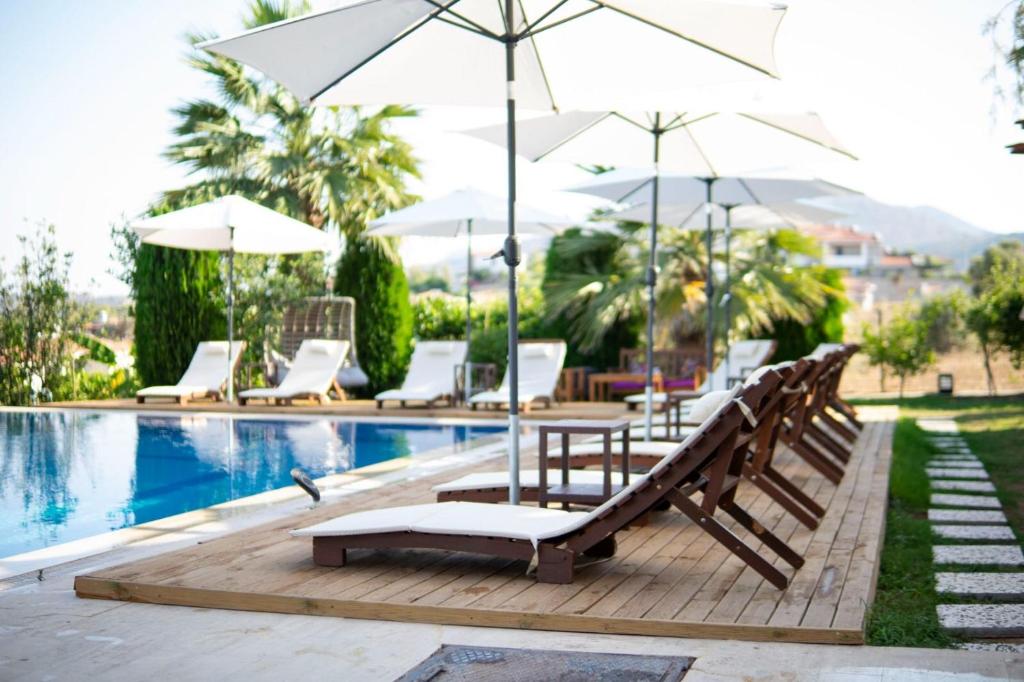 a pool with a table and chairs and umbrellas at MAVİ ROTA BUTİK OTEL in Datca