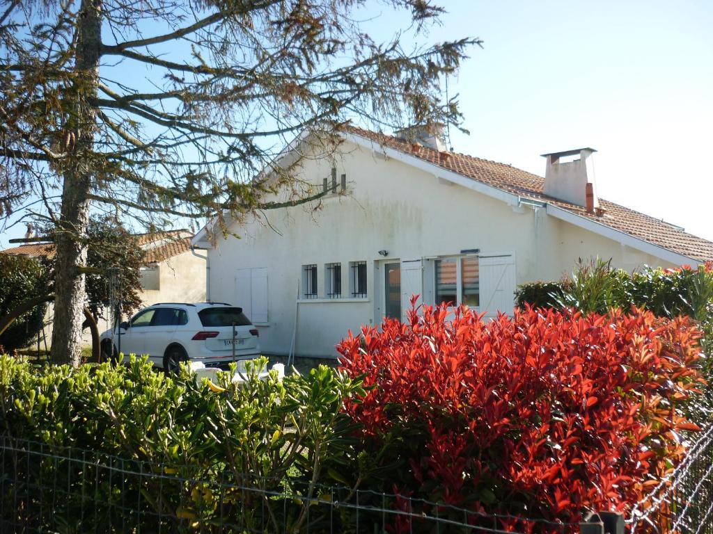une maison blanche avec des fleurs rouges devant elle dans l'établissement maison 20mn de la mer, à Aigrefeuille-dʼAunis