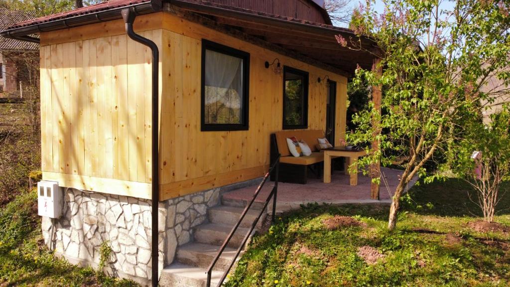 a small wooden cabin with a porch and a chair at Sole Tiny House in Šipovo