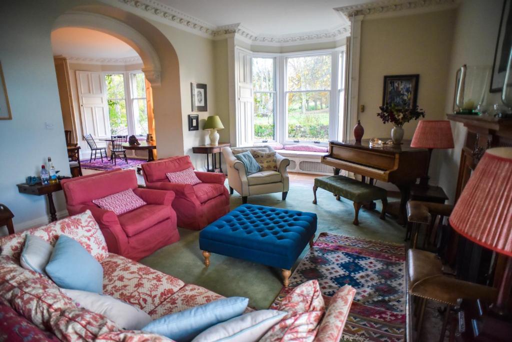 uma sala de estar com um sofá e um piano em Traditional Family Stone Farmhouse, sleeps 12, St Andrews em St. Andrews