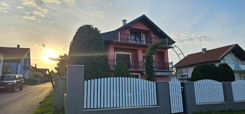 una casa roja con una valla blanca delante de ella en Guest House Lona en Golubac