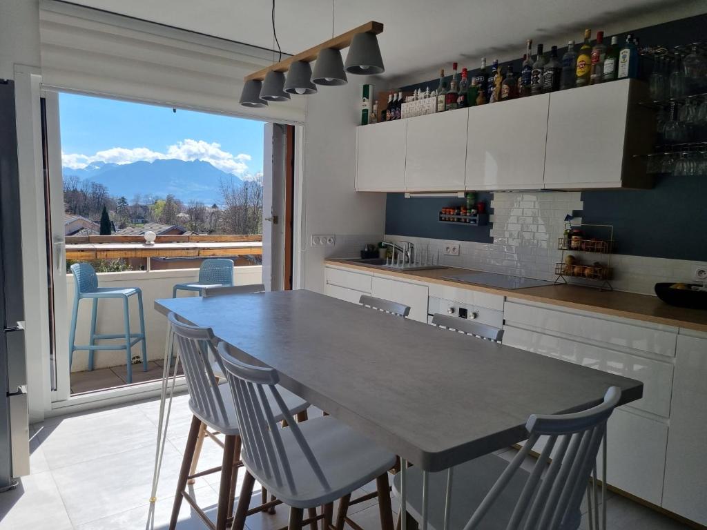a kitchen with a table and chairs and a large window at Calme à 2 pas du lac 3 chambres in Annecy