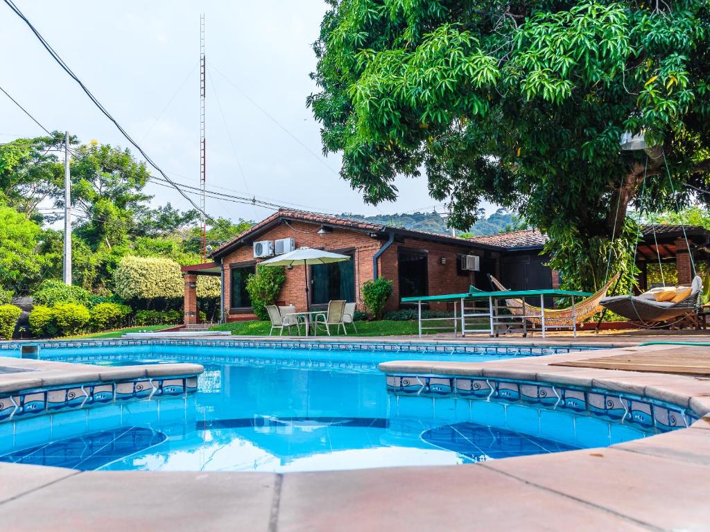 a swimming pool in front of a house at Quinta La Paloma in Itauguá