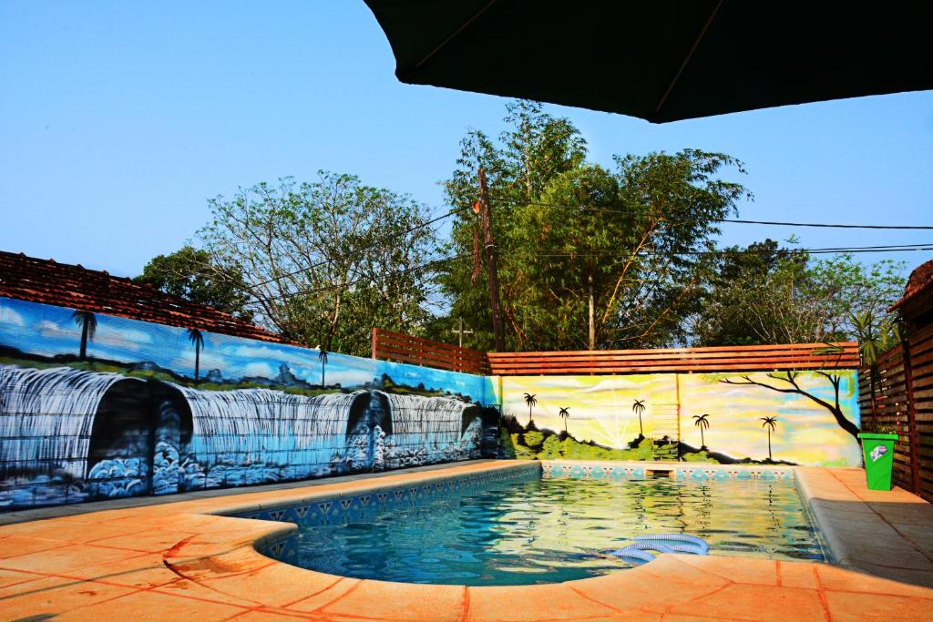 a swimming pool in front of a wall with a mural at Nuova Villa Cabañas in Puerto Iguazú