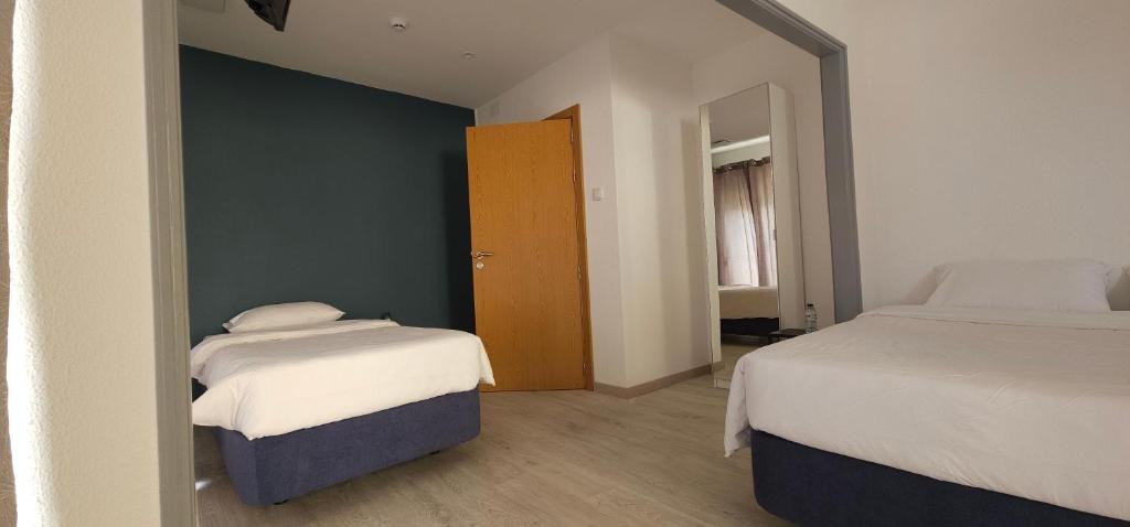 a bedroom with two beds and a mirror at Marinha Garden Inn in Marinha Grande